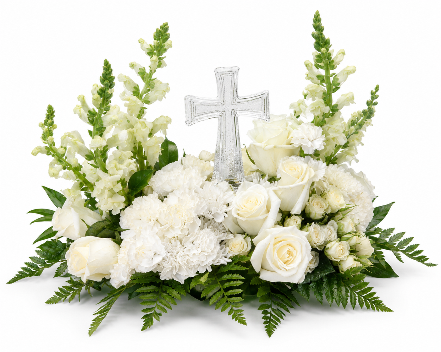 A Christian sympathy arrangement featuring a clear glass cross surrounded by white roses, white spray roses, snapdragons, carnations, white chrysanthemums, and lush green fern. The elegant all-white floral design symbolizes faith, grace, peace, and everlasting remembrance, making it a meaningful tribute for funeral services, memorials, or celebrations of life.