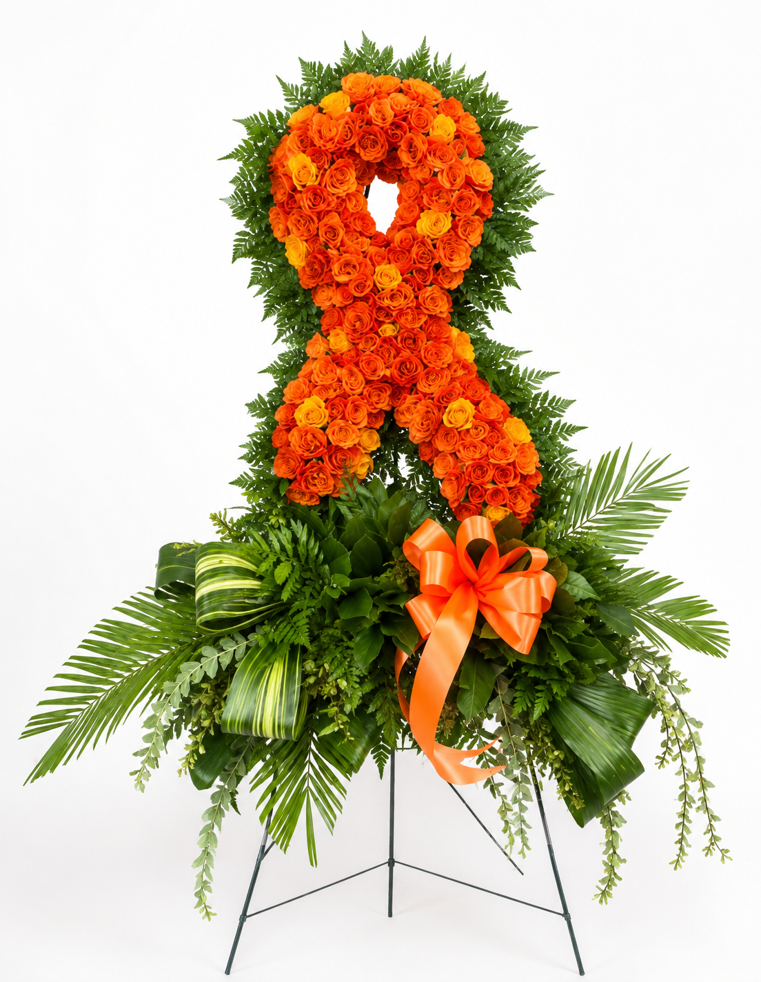 An orange awareness ribbon floral arrangement made of orange flowers, surrounded by green foliage and a large orange bow, displayed on a black metal stand against a white background.