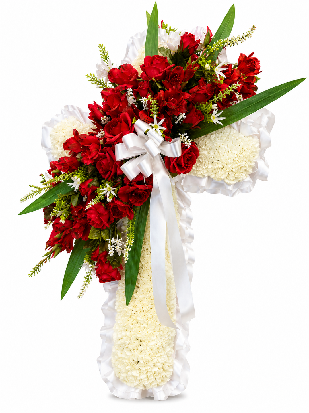A large floral cross grave flower arrangement featuring red floral spray, white carnations, green foliage, and a white satin ribbon bow, set against a plain white background.