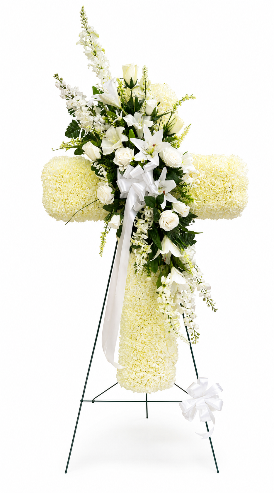 Elegant heart-shaped sympathy wreath made of artificial candlestick white carnations, accented with artificial white lilies, artificial white roses, artificial lush greenery, and a flowing white ribbon, displayed on a white easel against a clean neutral background.