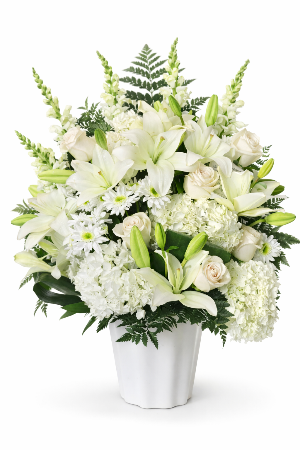 Classic white sympathy arrangement featuring white lilies, ivory roses, white hydrangea, white daisies, and lush fern greenery, designed in a full, elegant style and displayed in a white urn against a clean white background.