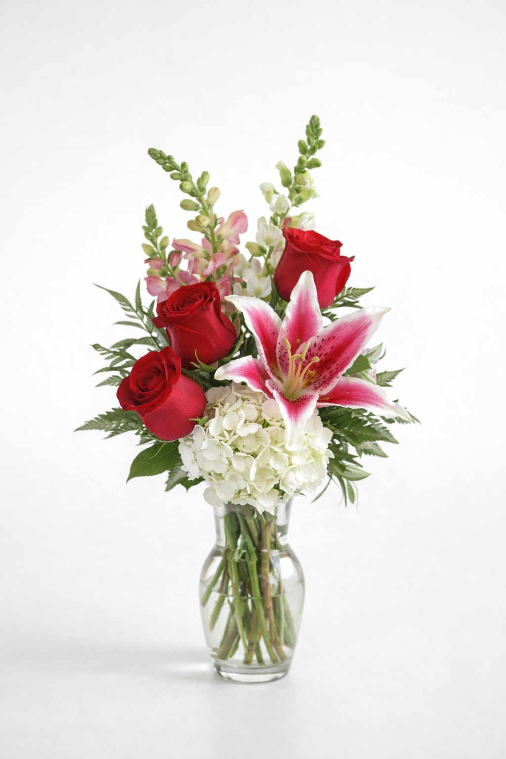 My Princess floral arrangement featuring red roses, pink lilies, white hydrangea, and greenery arranged in a clear glass bud vase.