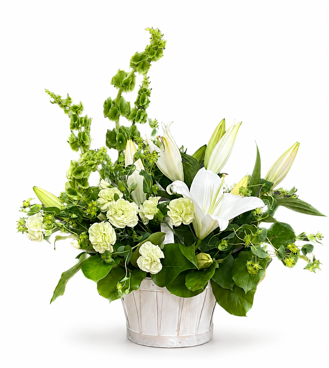 A floral arrangement featuring white lilies, pale green hydrangeas, and green foliage in a white ribbed bucket-style vase, photographed on a clean white background.