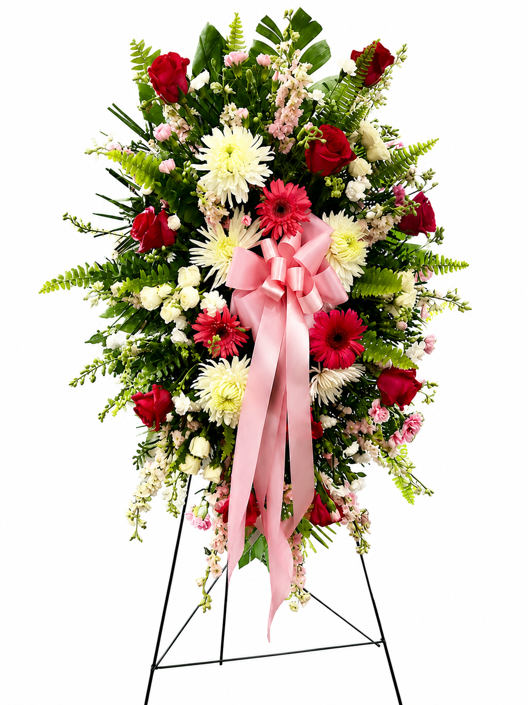 Elegant standing sympathy spray featuring pink and red roses, pink gerbera daisies, white chrysanthemums, soft filler flowers, and lush greenery, accented with a flowing pink satin ribbon and displayed on a green easel against a neutral background.