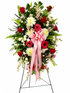 Elegant standing sympathy spray featuring pink and red roses, pink gerbera daisies, white chrysanthemums, soft filler flowers, and lush greenery, accented with a flowing pink satin ribbon and displayed on a green easel against a neutral background.